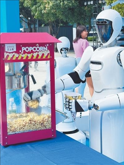 광둥(廣東) 포산(佛山)시 한 산업단지에서 메이디(美的, Midea) 휴머노이드 로봇 ‘메이라’(美拉)가 팝콘 기계를 조작해 단지 내 직원들에게 서비스를 제공한다. [사진 출처: 인민시각/촬영: 리차이창(李彩暢)]